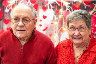 Two senior residents smiling in a festive setting