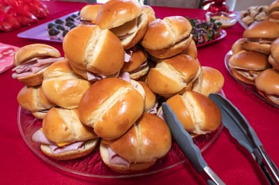 A plate of sandwich sliders on a red tablecloth