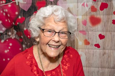 Smiling resident with curly hair and glasses in a festive setting