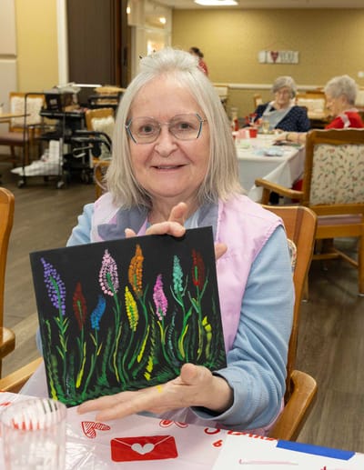 Resident showcasing her painting in a common area