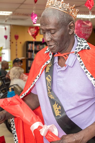 Resident celebrating with a crown and cape during an event