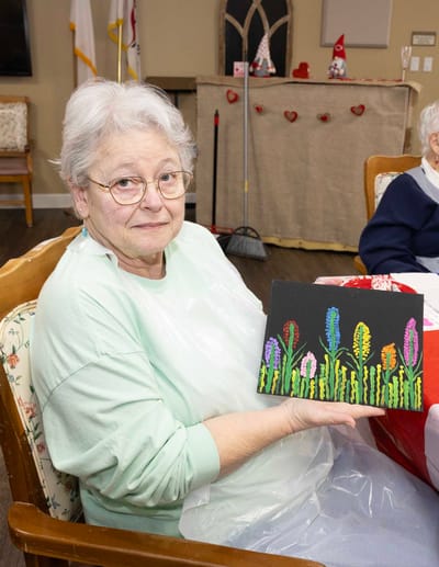 Resident showcasing a flower painting during an activity