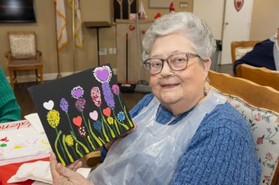 Resident painting flowers in an activity room