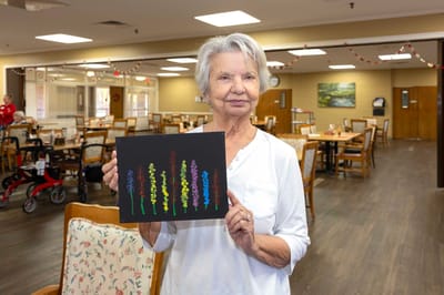 Resident showcasing her artwork in a common area