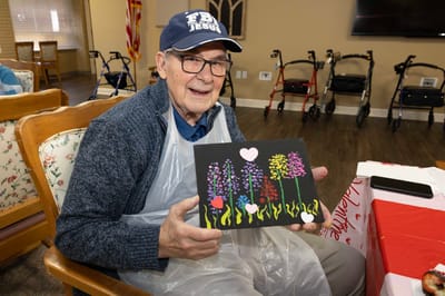 Resident painting a colorful floral artwork in an activity room