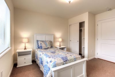 A cozy resident room with a bed and lamp