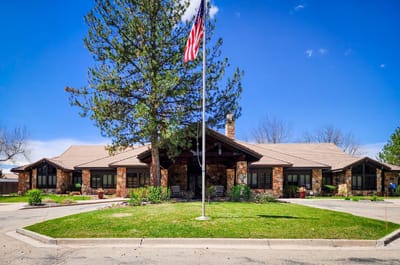 Exterior view of a senior living facility with a flag and trees