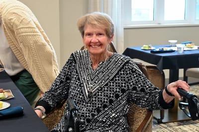 A resident smiling in a common area during a meal