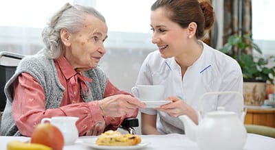A caregiver serving tea to a senior resident