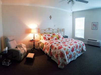 A private resident room with floral bedding and armchair