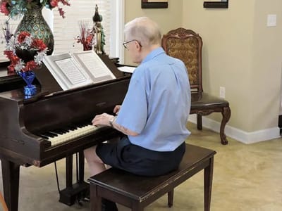 Resident playing piano in a common area