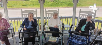 Residents enjoying time on a porch with rocking chairs