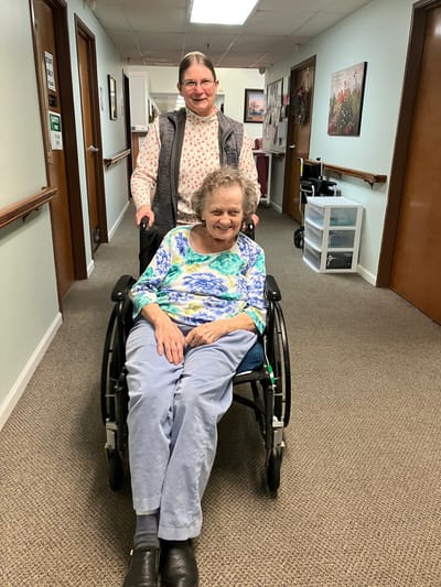Staff member pushing a resident in a wheelchair in a hallway