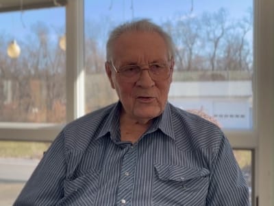 An elderly man sitting in a bright room with a view