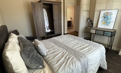 Brightly lit room with a bed and wardrobe