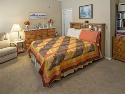 Cozy resident room with quilted bedspread and personal touches