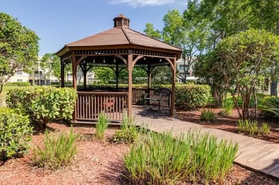 A wooden gazebo in a landscaped garden