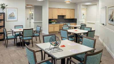 Bright activity room with tables, chairs, and bingo equipment
