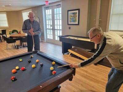 Two residents enjoying a game of billiards in the activity room