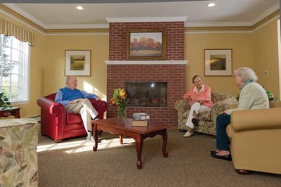Residents chatting in a cozy common area with a fireplace