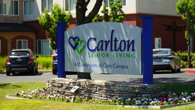Sign for Carlton Senior Living with landscaped garden