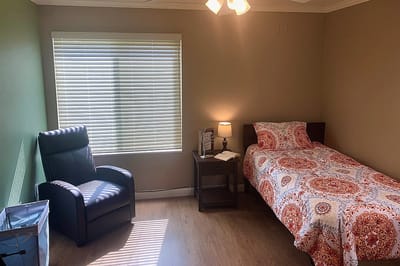 A cozy resident room with a bed and chair
