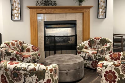 Cozy common area with floral chairs and a fireplace