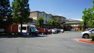 Exterior view of a senior living facility with parked vehicles