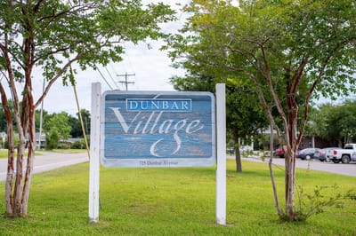 Sign for Dunbar Village with trees and grass
