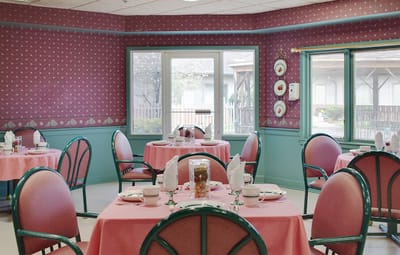 Dining area set for a meal with tables and chairs