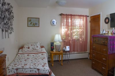 A private resident room with a bed and dresser