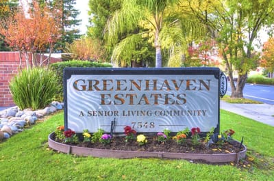 Exterior signage for Greenhaven Estates with colorful landscaping
