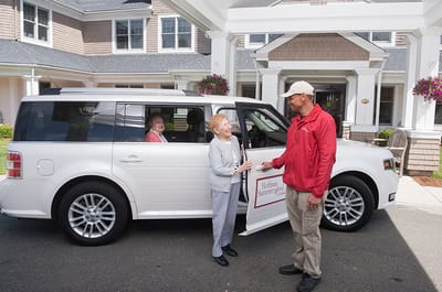 Resident interacting with staff by the facility transport van