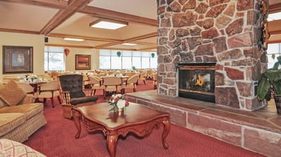 Cozy dining room with stone fireplace and tables set for meals