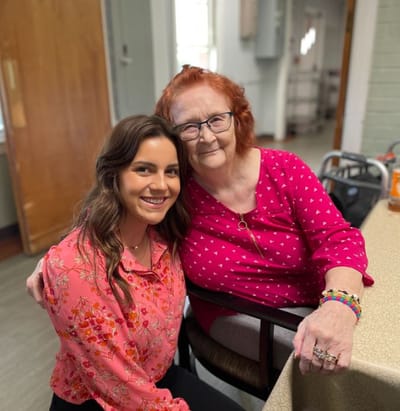 Resident and staff member smiling together in an indoor setting