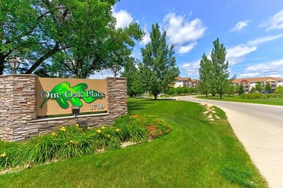 Entrance sign for One Oak Place with landscaped surroundings