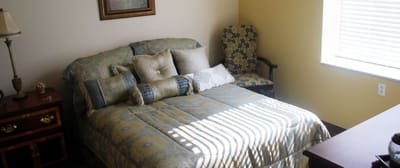 Cozy resident room with a large bed and armchair