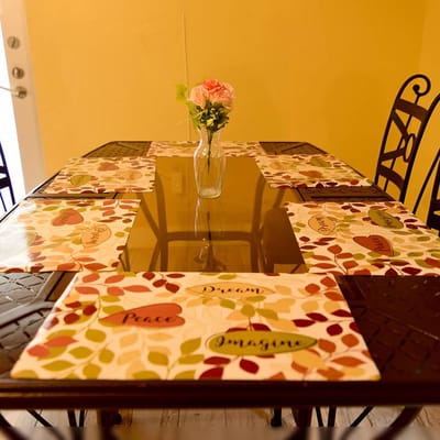 Dining table setup with a flower vase and placemats