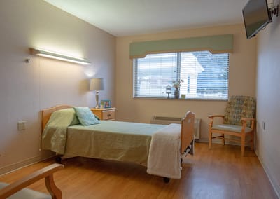 Bright and clean resident room with a bed and chair