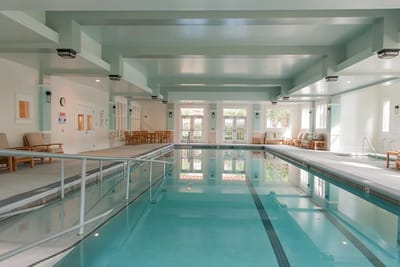 Indoor pool area with lounge chairs and large windows