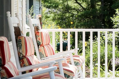 Rocking chairs on a porch overlooking a garden