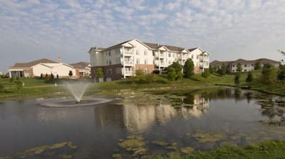 Exterior view of The Fountains by a pond with fountain