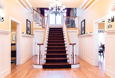 Bright interior hallway with stairs and chandeliers
