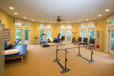 Rehabilitation gym with exercise equipment and large windows