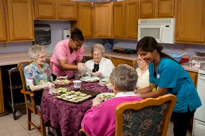 Residents and staff preparing food in a kitchen