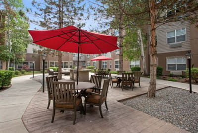 Outdoor seating area with red umbrellas and trees