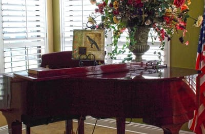 Interior of a cozy common area with a piano and flowers