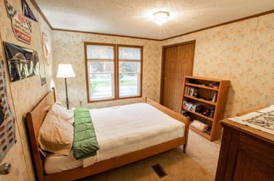 A well-lit bedroom with floral wallpaper and bookshelves