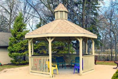 A gazebo in an outdoor area with colored chairs