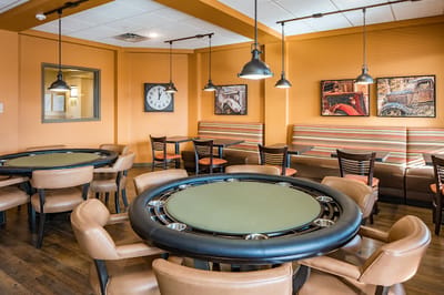 A game room with poker tables and orange walls